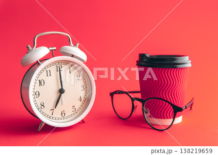White alarm clock, paper cup and glasses on Viva Magenta. 138219659