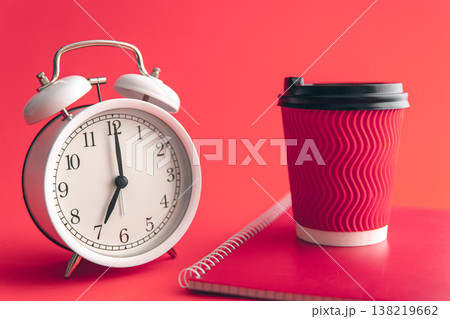 White alarm clock, paper cup and notepad on a blurred background. 138219662