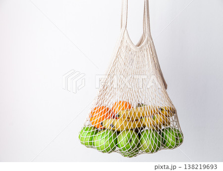 White string bag with green apples, oranges and bananas on a white background. White string bag with green apples, oranges and bananas on a white background. 138219693