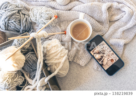 Yarn threads, knitted elements and a cup of coffee, top view. 138219839