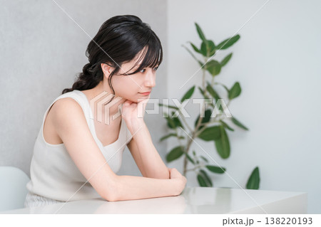 頬杖をつき悩む,考えるタンクトップ姿の若いアジア人女性 138220193