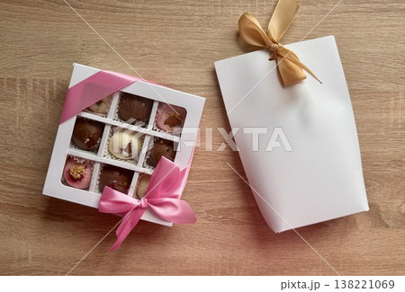 Delicious, sweet handmade chocolates made of white and milk chocolate with whole nuts in a gift box on a light background 138221069
