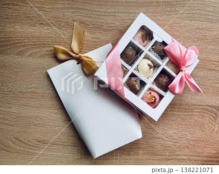 Delicious, sweet handmade chocolates made of white and milk chocolate with whole nuts in a gift box on a light background 138221071