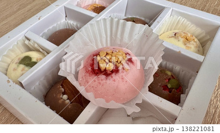 Delicious, sweet handmade chocolates made of white and milk chocolate with whole nuts in a gift box on a light background Delicious, sweet handmade chocolates made of white and milk chocolate with whole nuts in a gift box on a light background 138221081