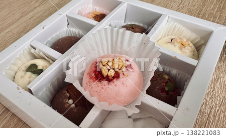 Delicious, sweet handmade chocolates made of white and milk chocolate with whole nuts in a gift box on a light background 138221083