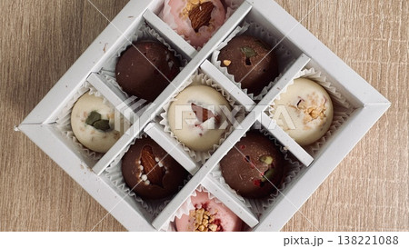 Delicious, sweet handmade chocolates made of white and milk chocolate with whole nuts in a gift box on a light background Delicious, sweet handmade chocolates made of white and milk chocolate with whole nuts in a gift box on a light background 138221088