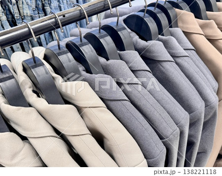 New stylish classic cut jackets in pastel shades are hanging on hangers in a clothing store New stylish classic cut jackets in pastel shades are hanging on hangers in a clothing store 138221118