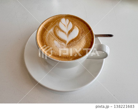 A white porcelain tea steamer stands on a coffee table with a delicious fragrant cappuccino poured to the brim. A white porcelain tea steamer stands on a coffee table with a delicious fragrant cappuccino poured to the brim. 138221683