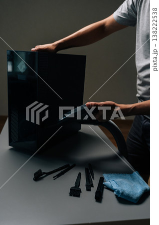 Vertical cropped shot of computer technician cleaning computer case with vacuum cleaner, different brushes and microfiber cloth on table, performing maintenance and removing dust. 138222538