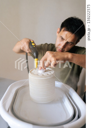 Vertical shot of technician cleaning air humidifier filter with professional steam cleaner, removing dust and allergens for improved indoor air quality and home wellness. Concept of healthy lifestyle. 138222575