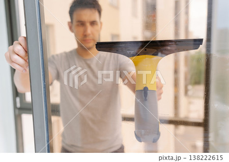 View from glass to janitor cleaning window with cordless vacuum cleaner, achieving spotless, streak-free shine in home environment while maintaining high standards of hygiene and cleanliness. View from glass to janitor cleaning window with cordless vacuum cleaner, achieving spotless, streak-free shine in home environment while maintaining high standards of hygiene and cleanliness. 138222615