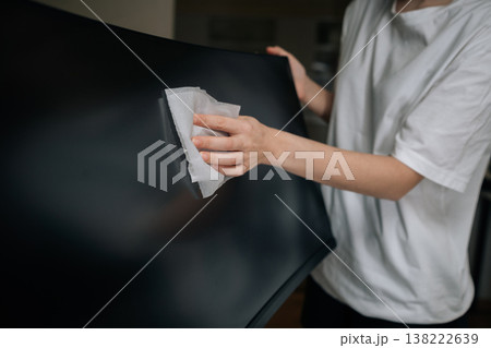 Cropped shot of person cleaning computer monitor screen with soft white cloth, wiping dust and smudges from display for improved hygiene and maintenance of electronic equipment. 138222639