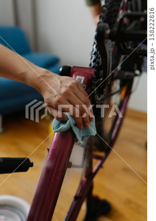 Bike mechanic spraying water on bicycle frame, wiping carefully with cloth during detailed workshop maintenance process, ensuring cleanliness and optimal performance. Concept of bicycle service. 138222816