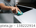 Close-up of male hand cleaning microwave oven with sponge, applying cleaner for sanitation and maintaining kitchen appliance hygiene, performing routine household chores. Concept of kitchen hygiene. 138222914