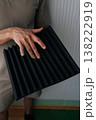 Close-up hand of handyman holding a black acoustic foam panel, exploring soundproofing materials for studio environment, noise reduction, and audio quality improvement projects. 138222919