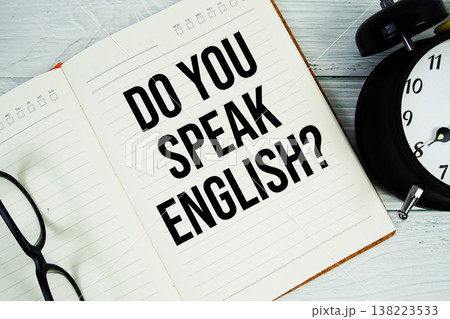 Notepad on a blue wooden table with the words "Do You Speak English?" with alarm clock and eyeglasses Notepad on a blue wooden table with the words "Do You Speak English?" with alarm clock and eyeglasses 138223533