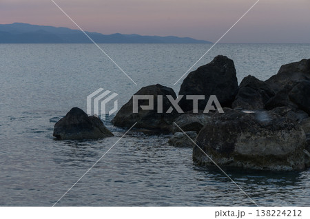 Tranquil twilight over rugged rocks and gentle waves by the serene coastline at dusk 138224212