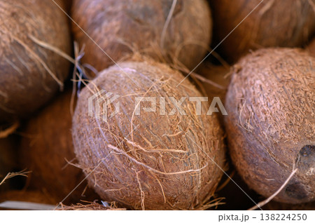 Unique coconuts nestled together in a vibrant market bustling with life during a sunny afternoon 138224250