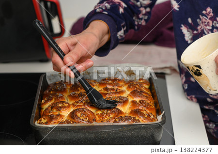 Freshly baked treats emerging from the oven as a cook adds a flavorful glaze using a brush to enhance the golden crust in a cozy kitchen setting Freshly baked treats emerging from the oven as a cook adds a flavorful glaze using a brush to enhance the golden crust in a cozy kitchen setting 138224377