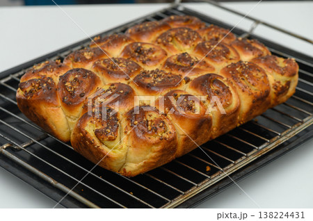 Freshly baked loaf of golden, pillowy rolls adorned with vibrant spices cooling on a rack in a cozy kitchen setting during the afternoon Freshly baked loaf of golden, pillowy rolls adorned with vibrant spices cooling on a rack in a cozy kitchen setting during the afternoon 138224431