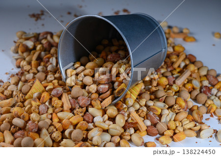 Colorful assortment of nuts spills from tin container creating a vibrant snack display on a bright surface 138224450