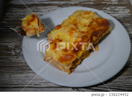 Delightful layers of cheesy chicken lasagna served on a rustic wooden table at sunset 138224452