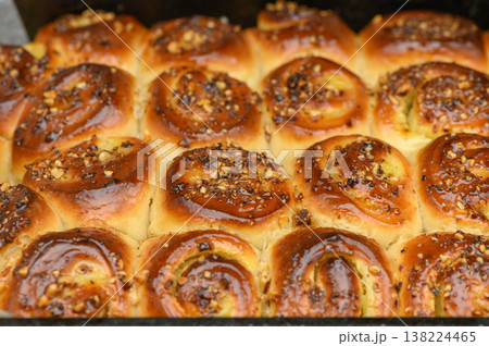 Warm, sweet cinnamon rolls topped with crunchy nuts fresh from the oven in a cozy kitchen setting 138224465