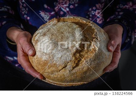 Freshly baked round loaf held by hands in a cozy kitchen setting, showcasing the art of bread making Freshly baked round loaf held by hands in a cozy kitchen setting, showcasing the art of bread making 138224566