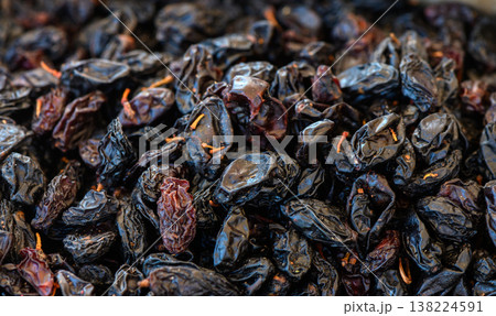 Dried fruits glisten under warm sunlight, showcasing their rich texture and deep color at a local market 138224591