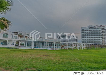Luxury resort buildings contrast with soft green lawns under an overcast sky in a serene coastal setting Luxury resort buildings contrast with soft green lawns under an overcast sky in a serene coastal setting 138224724
