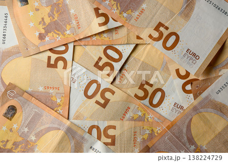 Stacks of 50 Euro banknotes spread out on a flat surface showcasing their vibrant designs and intricate details Stacks of 50 Euro banknotes spread out on a flat surface showcasing their vibrant designs and intricate details 138224729