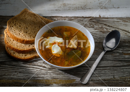 Warm soup with tender meat and fresh herbs served with rustic bread for a cozy Warm soup with tender meat and fresh herbs served with rustic bread for a cozy 138224807