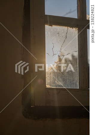 Sunlight filtering through a cracked window in an abandoned building at dusk Sunlight filtering through a cracked window in an abandoned building at dusk 138224821