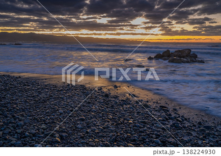 Beautiful sunset over rocky beach with waves gently lapping at the shore Beautiful sunset over rocky beach with waves gently lapping at the shore 138224930