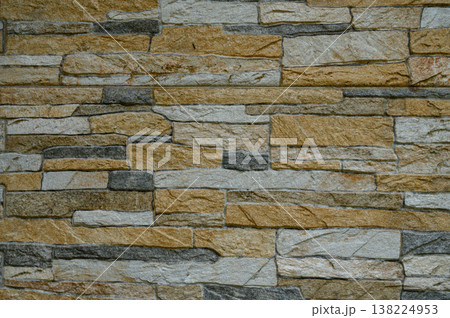 Natural stone wall with a blend of earthy tones and textures creating a rustic aesthetic 138224953