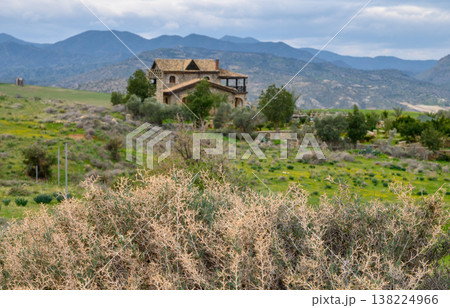Charming rustic house nestled in lush green landscape with mountains looming 138224966