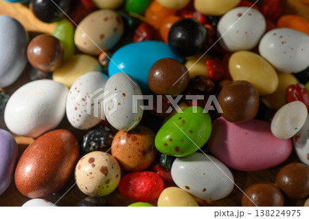 Colorful assortment of candy-coated treats scattered joyfully on a wooden surface Colorful assortment of candy-coated treats scattered joyfully on a wooden surface 138224975