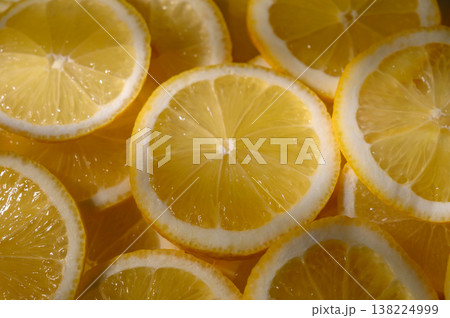 Fresh lemon slices arranged artfully on a wooden board, capturing vibrant yellow hues and juicy textures Fresh lemon slices arranged artfully on a wooden board, capturing vibrant yellow hues and juicy textures 138224999