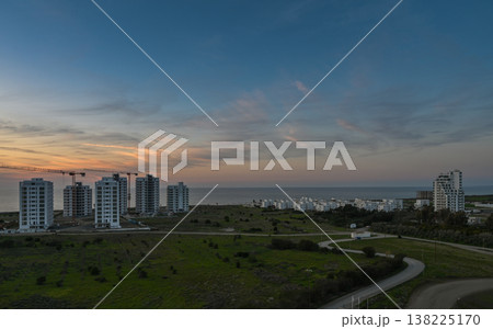 Coastal sunset illuminates modern buildings along the shoreline at dusk Coastal sunset illuminates modern buildings along the shoreline at dusk 138225170