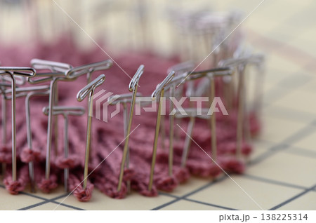 Close Up of Blocking Knitted Fabric with Metal T-Pins on White Close Up of Blocking Knitted Fabric with Metal T-Pins on White 138225314