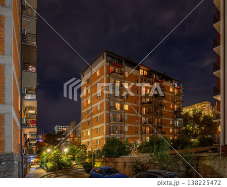 Jikia House Residential Complex in Tbilisi on a Rainy or Foggy Night. Reflections on Wet Asphalt and Atmospheric Haze. Jikia House Residential Complex in Tbilisi on a Rainy or Foggy Night. Reflections on Wet Asphalt and Atmospheric Haze. 138225472
