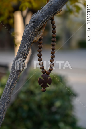 Boxwood Bead Cross Hanging on a Branch by the Wall of an Ancient Georgian Monastery. 138225590