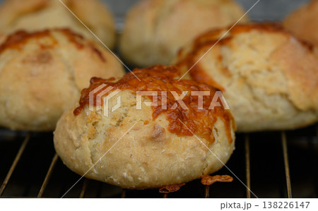 Freshly baked cheese rolls cooling on a wire rack in a cozy kitchen atmosphere during late afternoon sunlight Freshly baked cheese rolls cooling on a wire rack in a cozy kitchen atmosphere during late afternoon sunlight 138226147