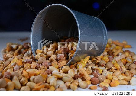 Colorful assortment of nuts and seeds spilling from a tipped metal bucket in a creative kitchen setup Colorful assortment of nuts and seeds spilling from a tipped metal bucket in a creative kitchen setup 138226299