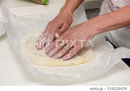 Woman preparing a fresh pizza in her kitchen. Kneading dough, spreading sauce, and adding toppings in a cozy and inviting home environment. Woman preparing a fresh pizza in her kitchen. Kneading dough, spreading sauce, and adding toppings in a cozy and inviting home environment. 138226429