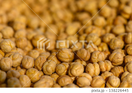 Dry chickpeas scattered in golden light highlight the texture and natural beauty of legumes in a warm setting 138226445