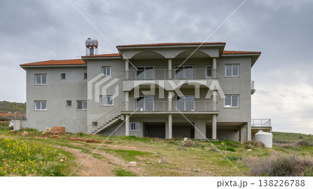 Modern countryside villa standing alone amidst tranquil fields on a cloudy day Modern countryside villa standing alone amidst tranquil fields on a cloudy day 138226788