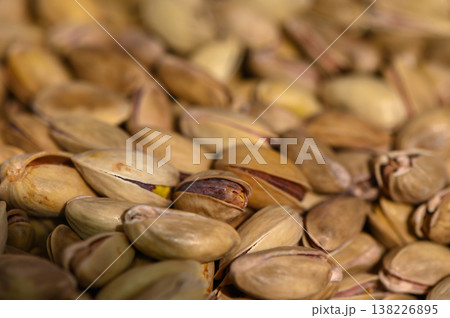 Pistachios scattered on a wooden surface create a natural and inviting texture in a rustic kitchen setting 138226895