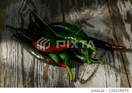 Fresh green and red chili peppers arranged artfully on rustic wooden background Fresh green and red chili peppers arranged artfully on rustic wooden background 138226974
