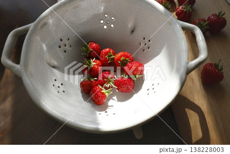 Fresh red strawberries in vintage ceramic colander on wooden table. Organic berries in white stoneware bowl with sunlight shadows, inspired by wabi-sabi and cottagecore aesthetic. Fresh red strawberries in vintage ceramic colander on wooden table. Organic berries in white stoneware bowl with sunlight shadows, inspired by wabi-sabi and cottagecore aesthetic. 138228003